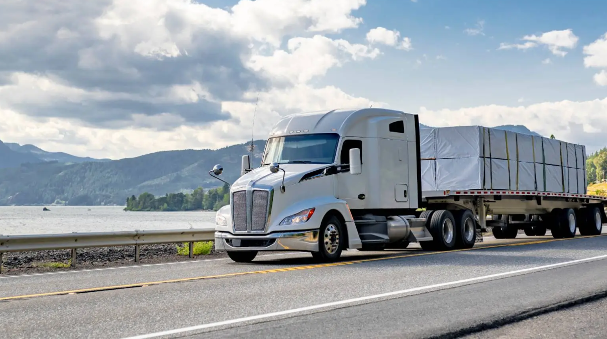 Flatbed Freight Services transporting oversized construction equipment on an open-deck trailer